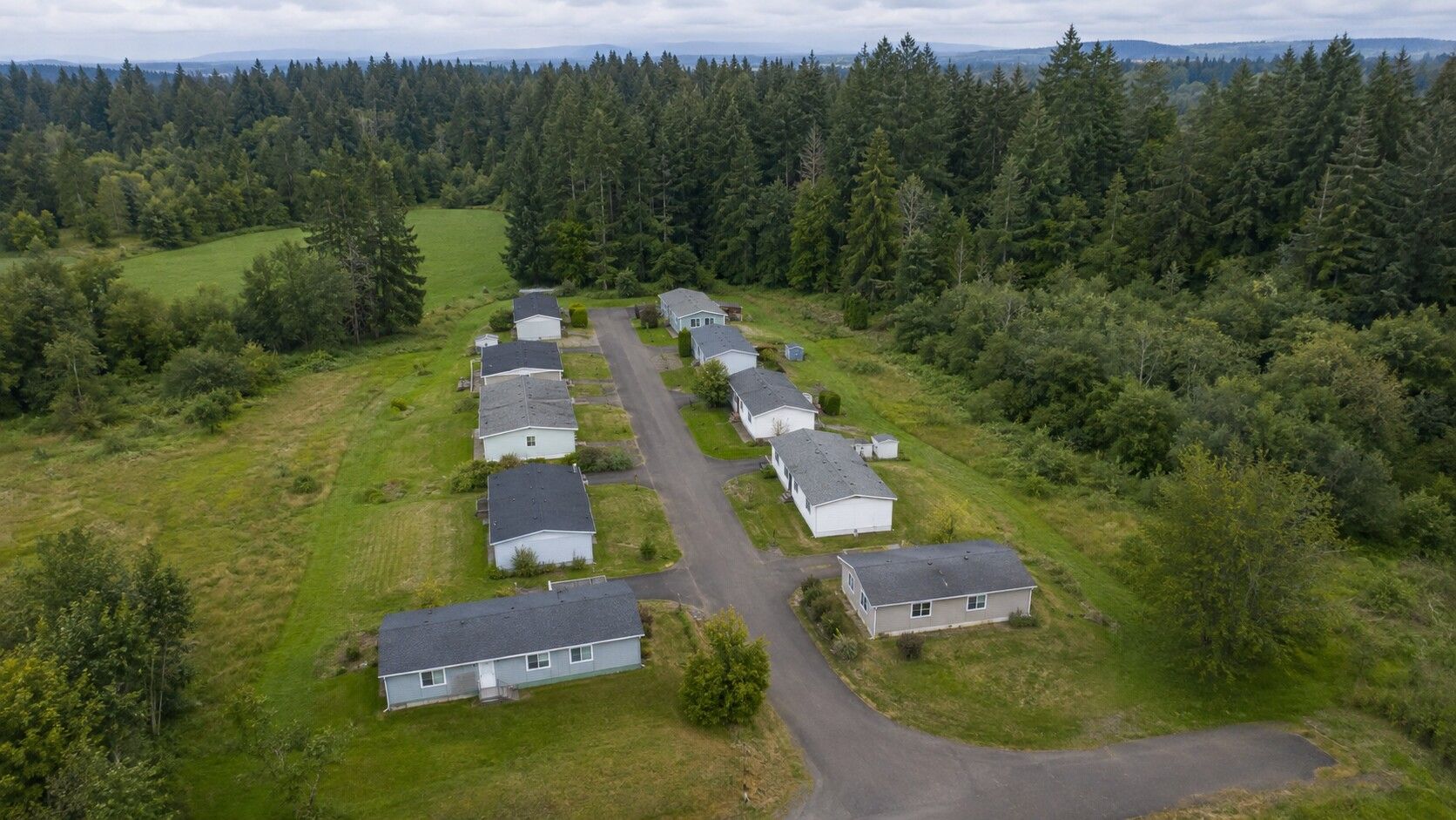 Aerial view of a small manufactured-home community surrounded by forest